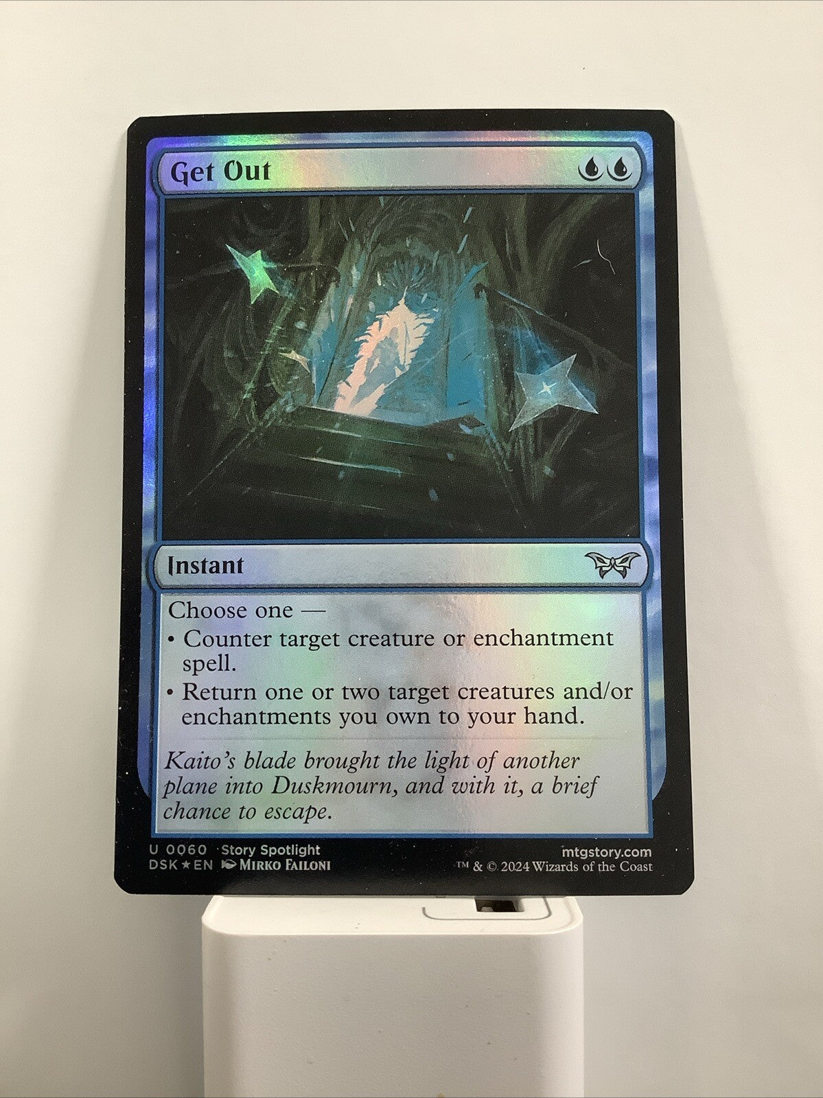 Magic: The Gathering foil Get Out instant card from Duskmourn House of Horror with reflective blue foil finish and glowing escape artwork